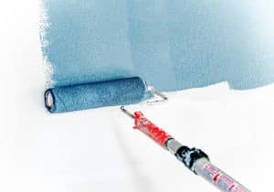 Blue paint roller painting a wall